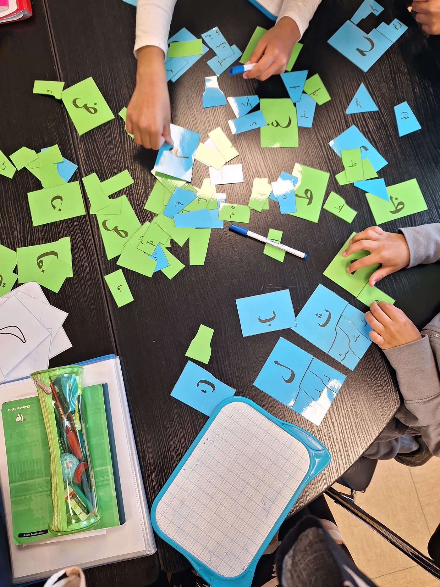 Mains d'enfants triant des lettres arabes en atelier Montessori